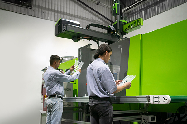 hombres trabajando en una máquina de inyección de plástico